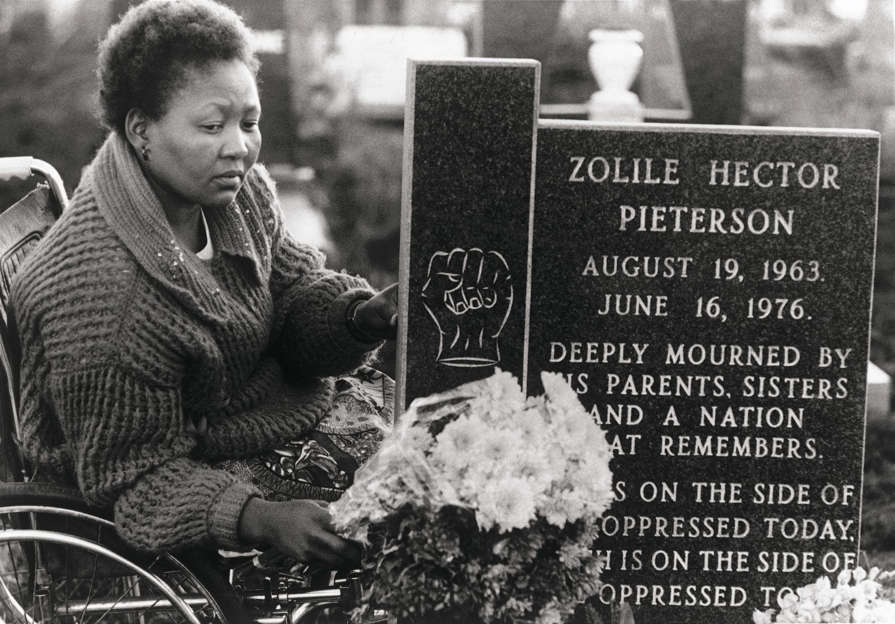 A woman injured during the Soweto uprising pays respect at the grave of Hector Pieterson.