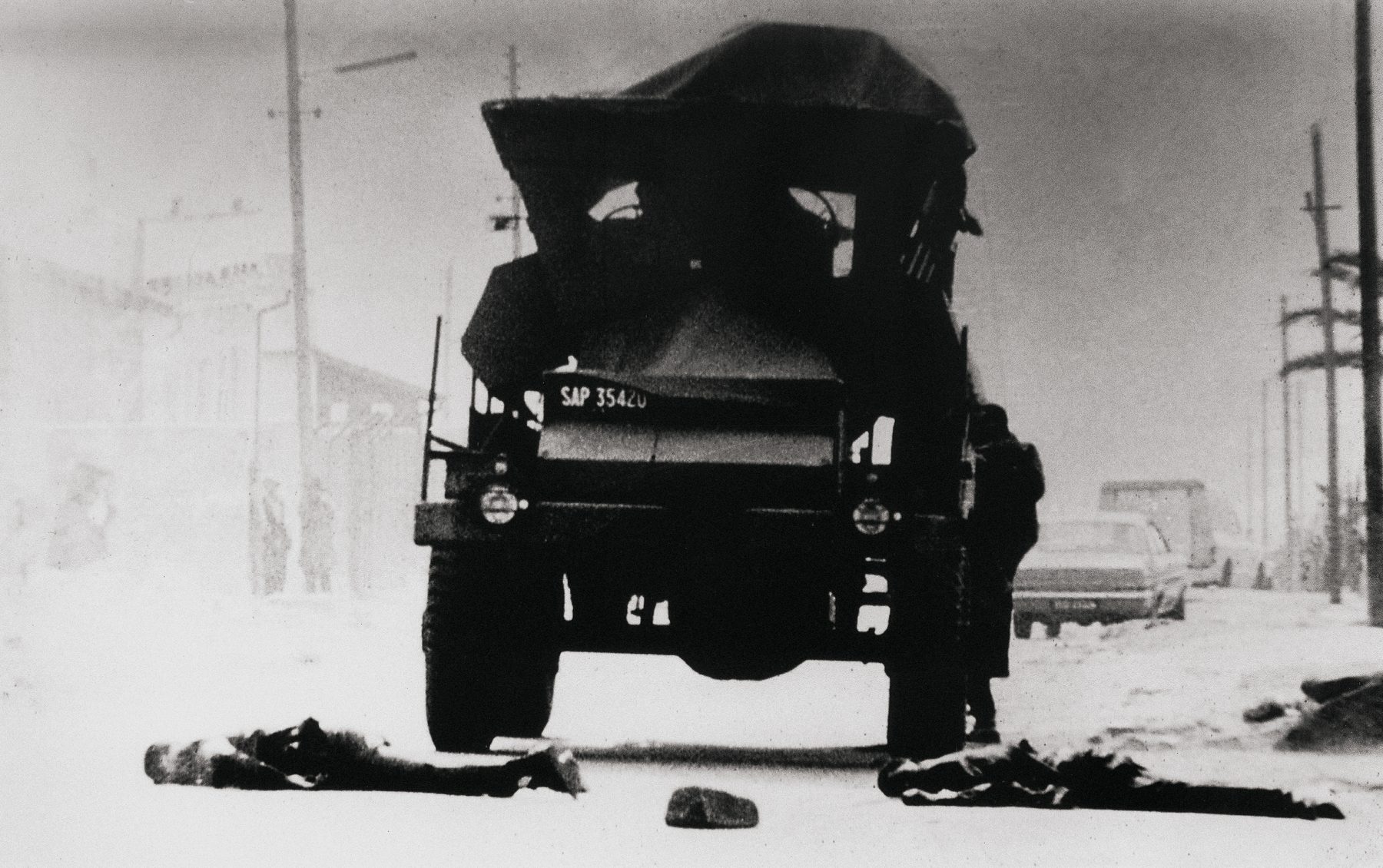 Dead lie before an army vehicle near Mzimhlope, days after June 16. Photographed by Alf Kumalo from the rear window of a car.